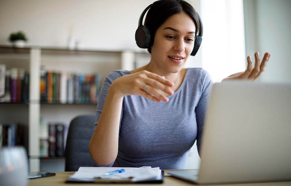 woman with earphones talking via computer