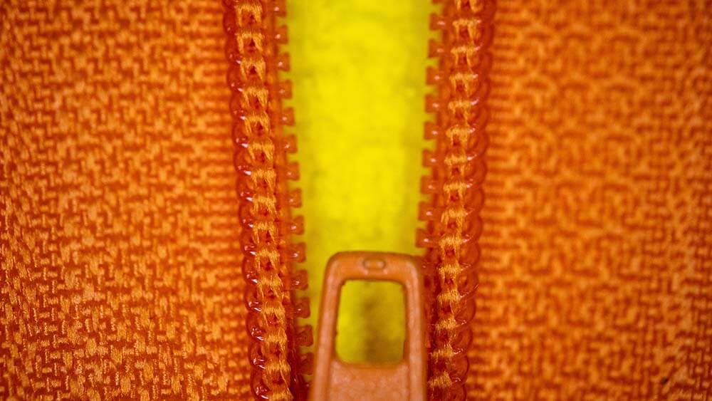 zippered orange jacket closing over yellow shirt