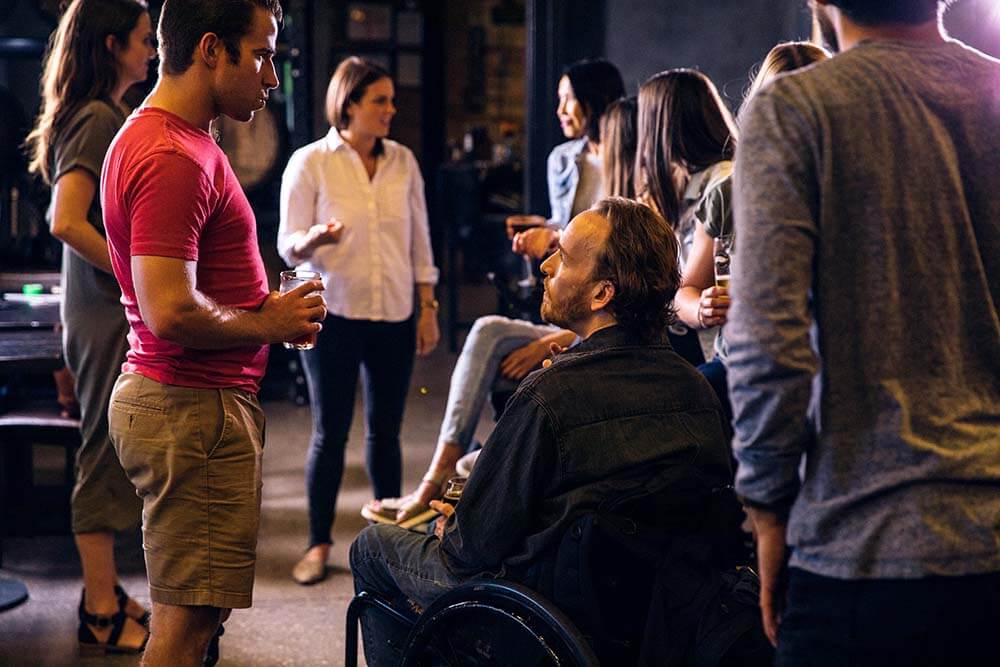 people chatting at event with one person in wheelchair