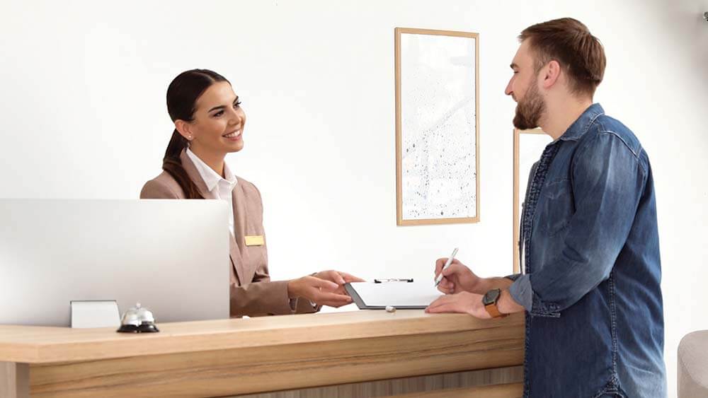 front desk attendant helps hotel guest