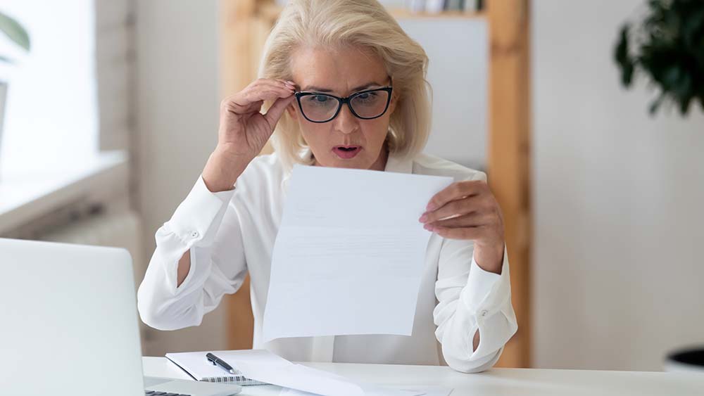 woman in glasses surprised by paper bill