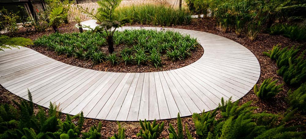 winding wooden walkway amidst large garden