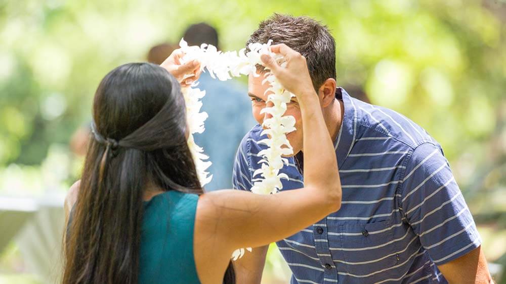 Hawaiian woman greeting tourist with a lai