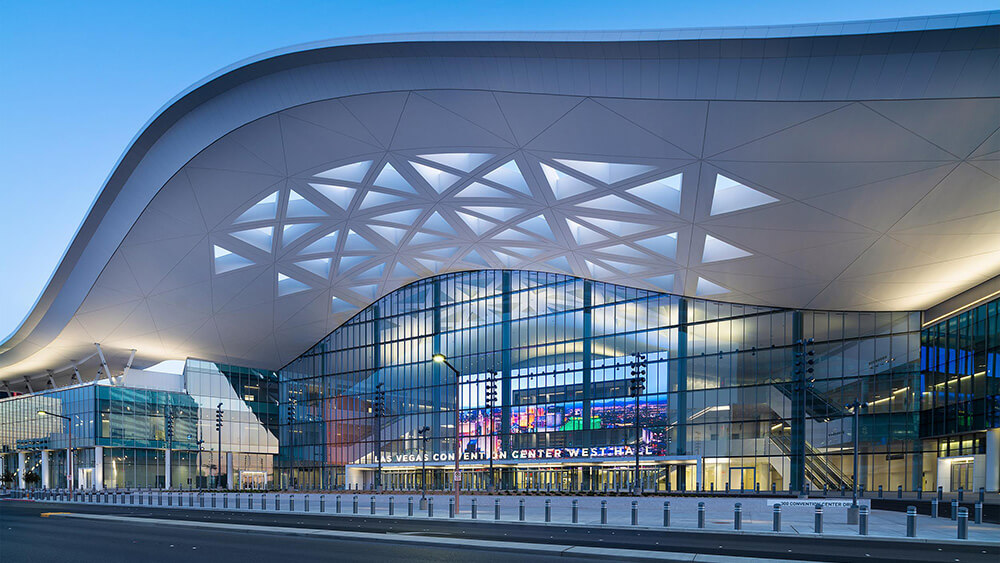 building with glass front and extended wavy white roof over entrance