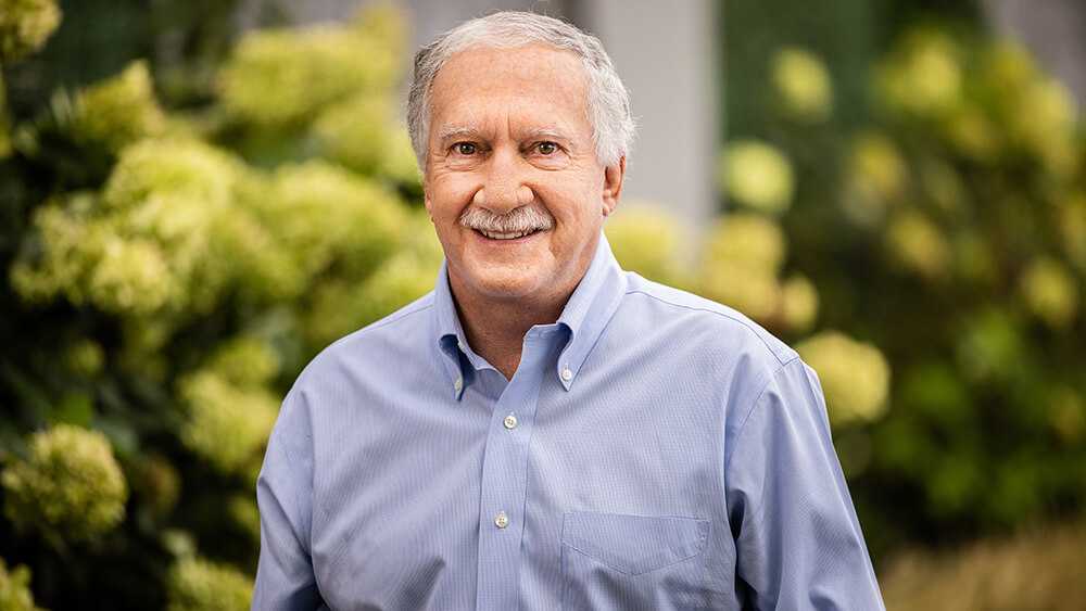 man with gray mustache, hair in blue shirt