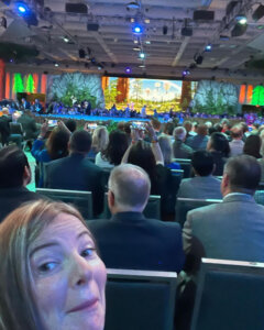 woman in selfie with conference stage behind her