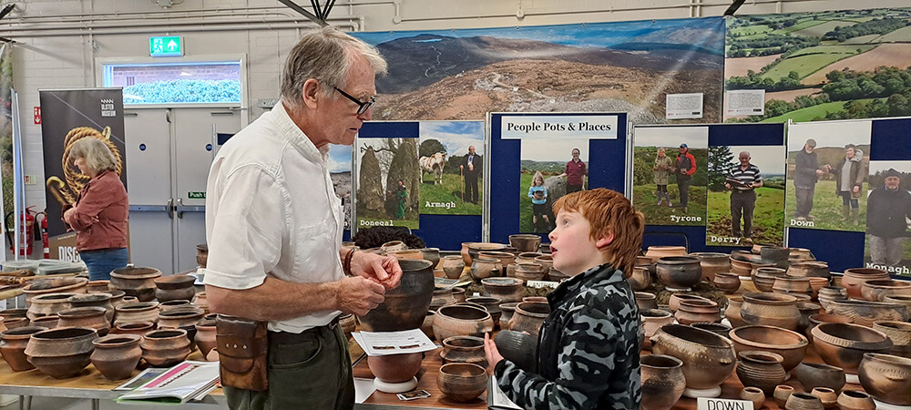 boy and man talking in room with prehistoric pots