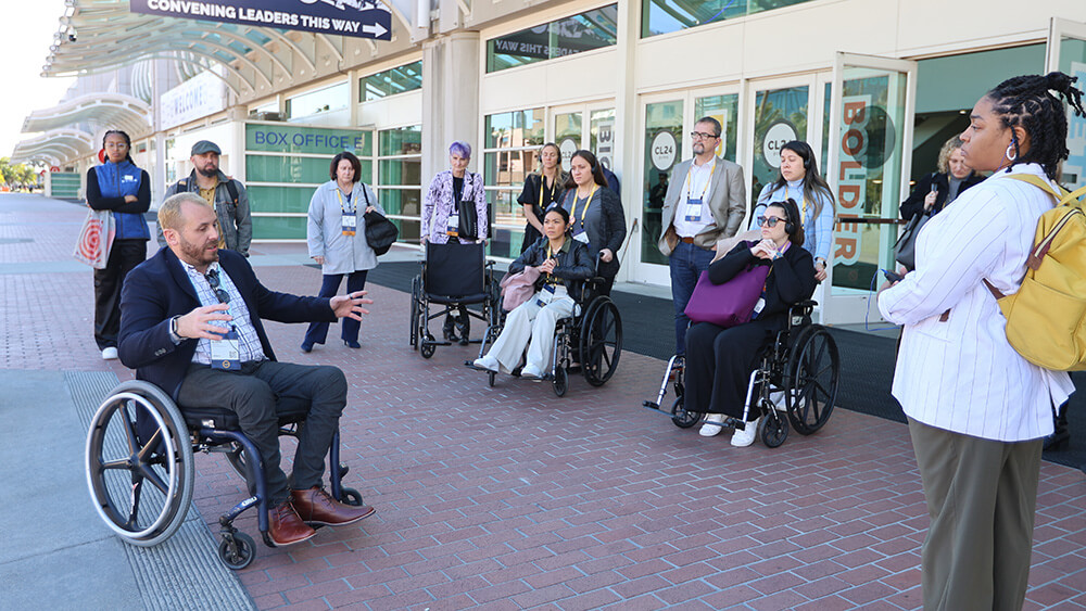 man in wheelchair leading tour with other people using wheelchairs