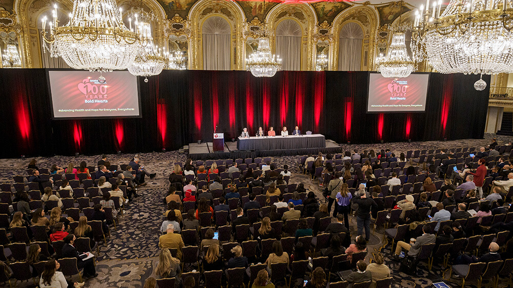 conference hall with filled seats and panel on stage