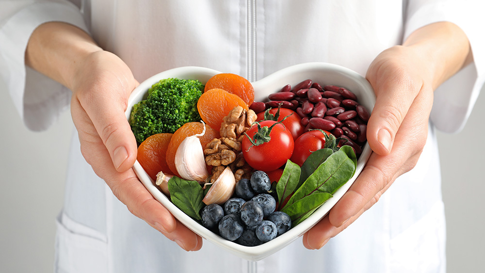hands holding heart-shaped bowl with fresh health foods